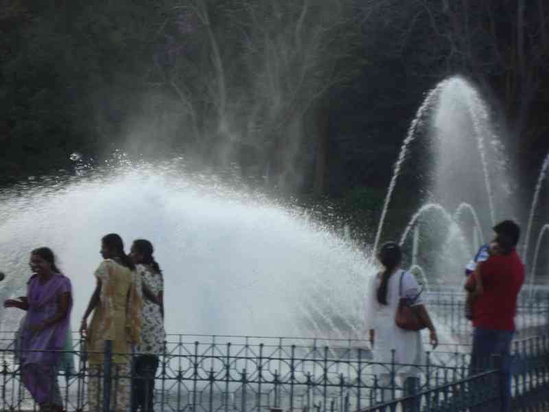 Une fontaine à eau, avec des jets d'eau s'élevant dans les airs, observée par une famille, photo gratuite