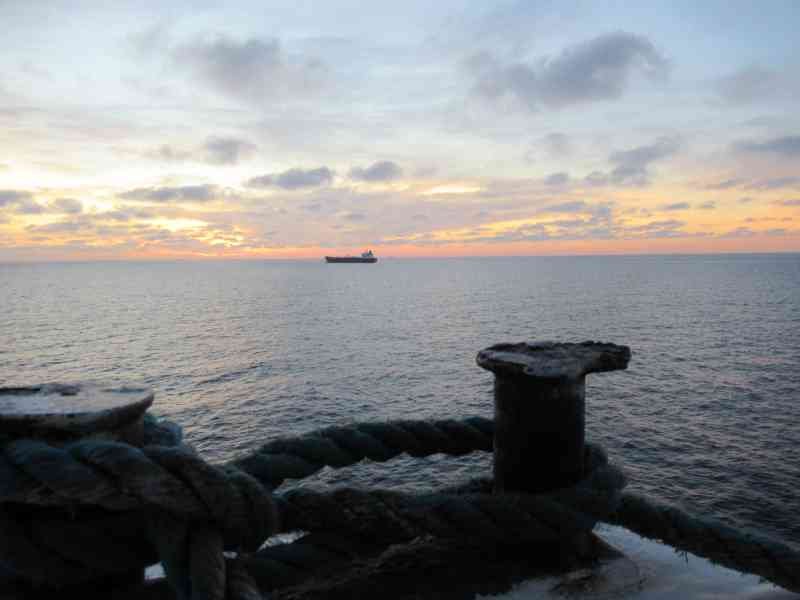 Corde épaisse est enroulée sur un bollard dans le port, bateau à l'horizon photo gratuite