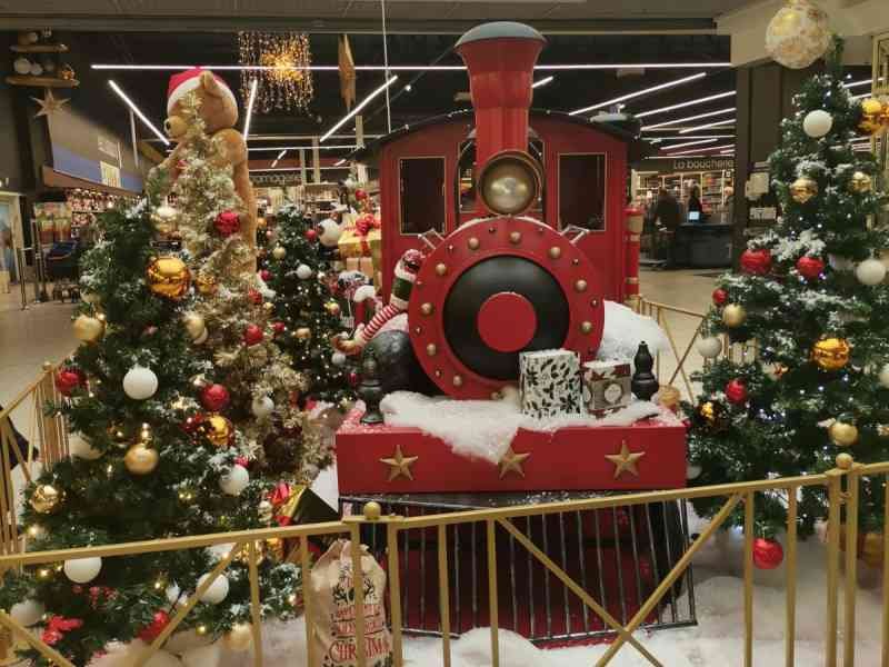 Sapins et train de Noël décorant l'intérieur d'un centre commercial